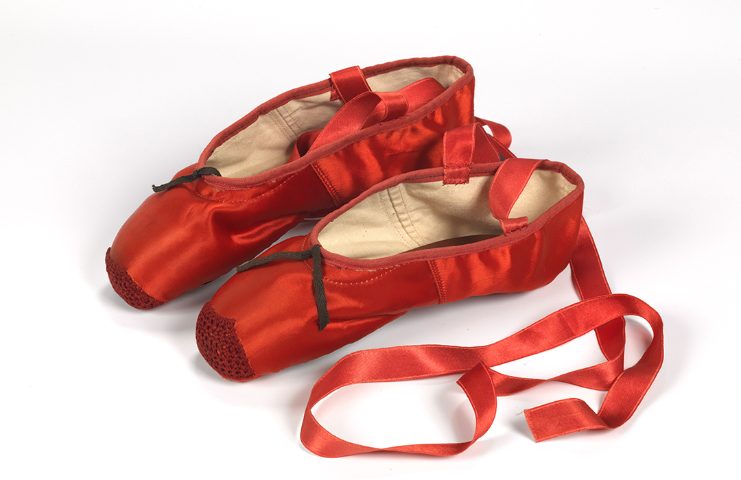 Red ballet shoes made for Victoria Page (Moira Shearer) in The Red Shoes (1948), silk satin, braid and leather, England, by Freed of London (founded in 1929), 1948, photograph reproduced with the kind permission of Northampton Museums and Art Gallery. 